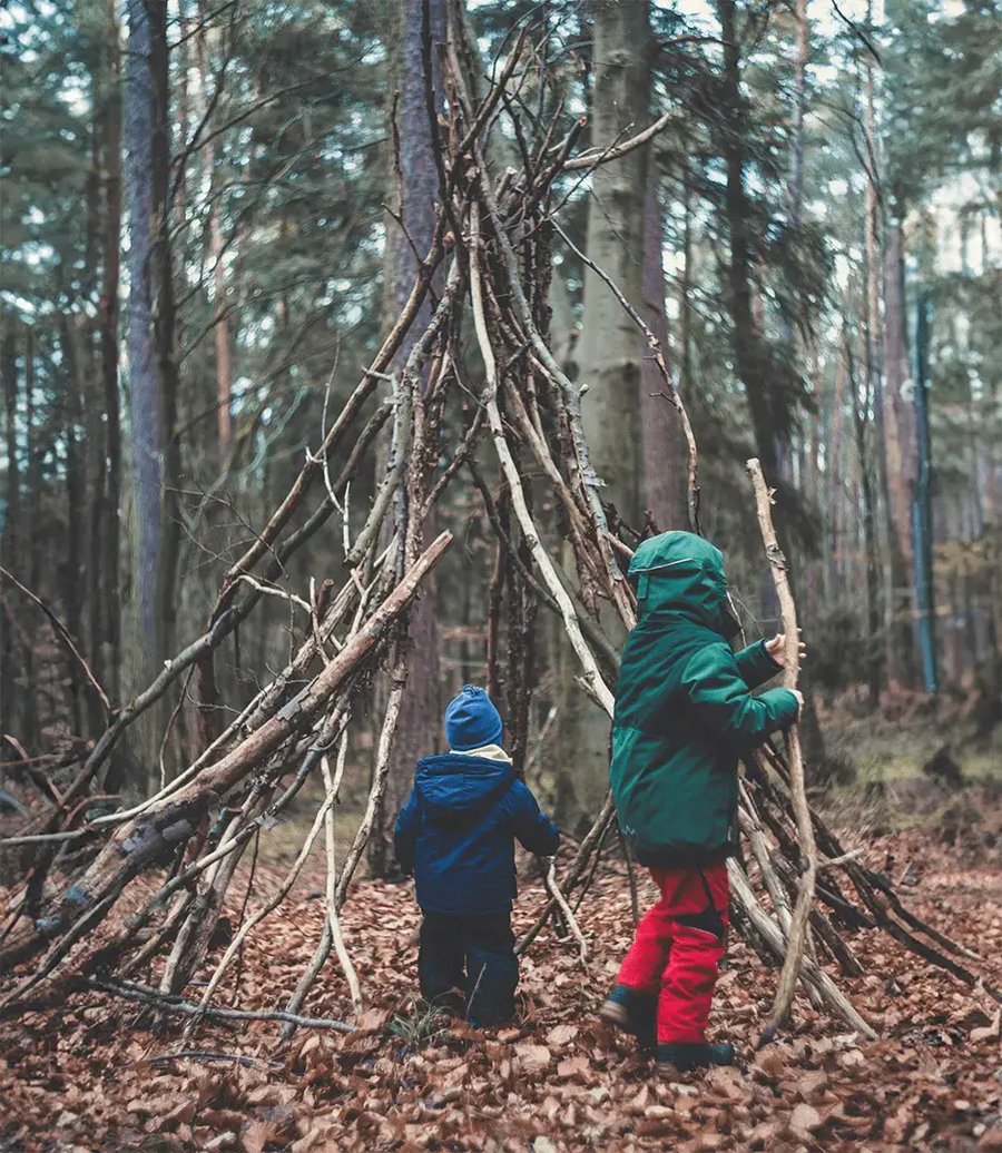 Due bambini costruiscono una capanna di legno nel bosco durante un'attività educativa all'aria aperta